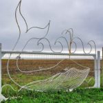 Baleia desenhada com varetas de metal em portão no litoral