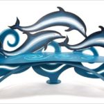 Banco escultural com golfinhos saltando sobre as ondas azuis