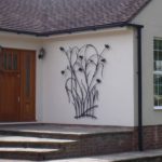Painel de ferro forjado com flores e pássaros na fachada de casa